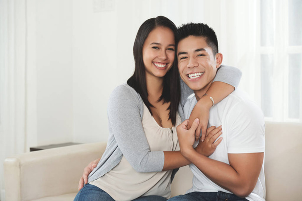 Happy young mixed-race couple hugging and smiling at camera - Foto, Imagen