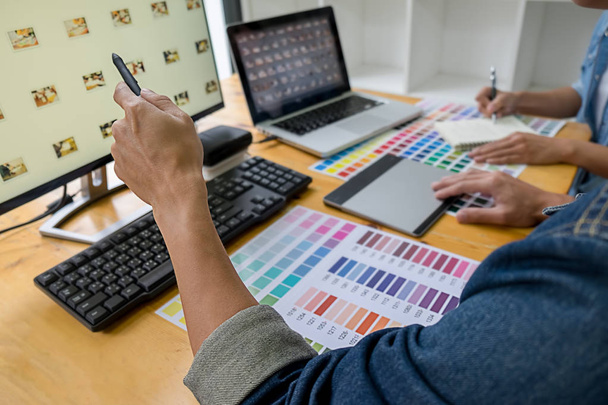 Grafikdesign mit Farbmustern und Tablet auf einem Schreibtisch. Grafikdesignerin zeichnet im Büro etwas auf Tablet mit Arbeitsgeräten und Zubehör. - Foto, Bild