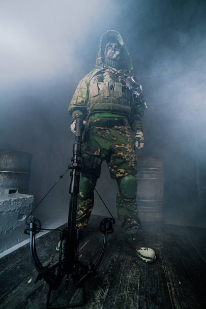 warrior in camouflage with crossbow posing against dark background - Zdjęcie, obraz