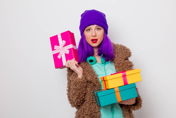 Krásná mladá dívka s fialovými vlasy v bundě s dovolené dárkové krabičky na bílém pozadí. - Fotografie, Obrázek