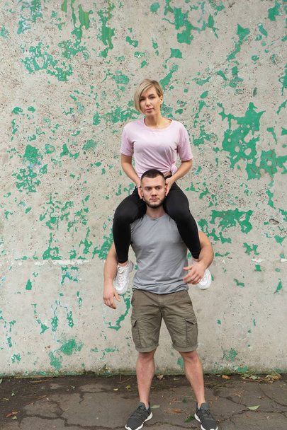 A girl is sitting on the shoulders of a guy, exercises with its own weight - Fotografie, Obrázek