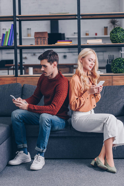young couple sitting back to back and using smartphones, relationship problem concept - Фото, зображення