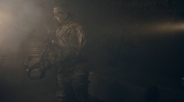 warrior man in camouflage with crossbow looking around in dark - Foto, imagen