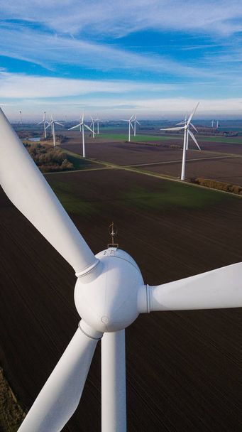 空撮から風力タービン。タービンに近い。持続可能な開発、環境にやさしい。明るい夏の日の中に風力発電機。風車。夏の日に農業分野. - 写真・画像