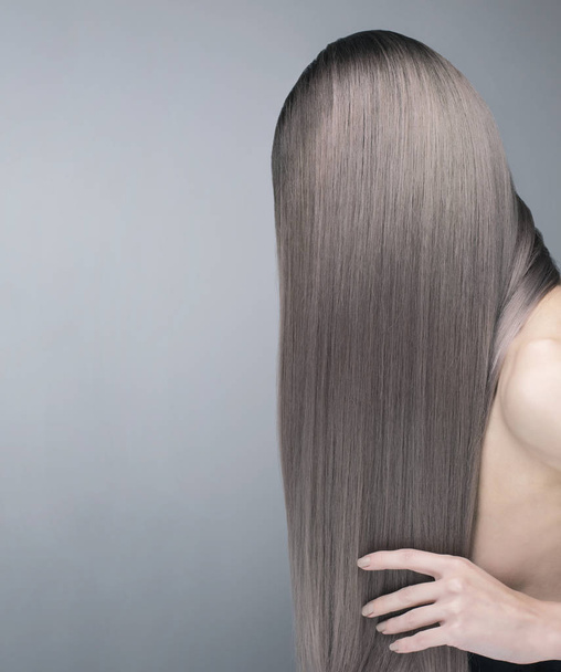 Anonieme shot van een perfecte lange en glanzend paars haar. Studio opname over grijze achtergrond. - Foto, afbeelding