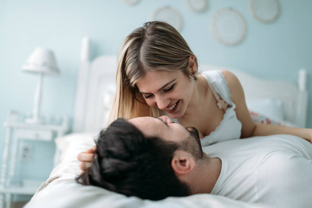 Portrait of young attractive loving couple in bedroom - Фото, изображение