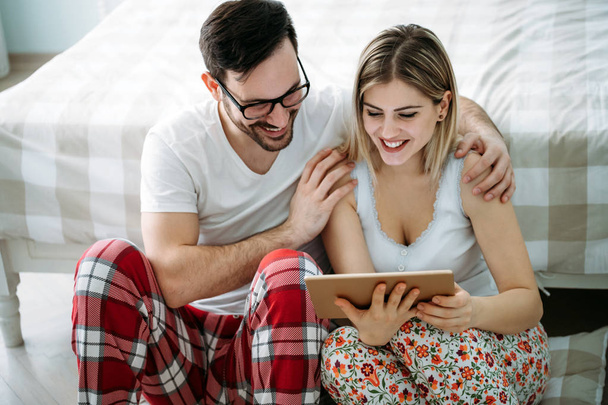 Young happy couple using digital tablet in bedroom - Φωτογραφία, εικόνα