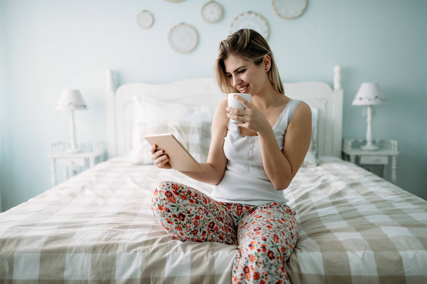 Молода красива жінка використовує цифровий планшет у спальні
 - Фото, зображення