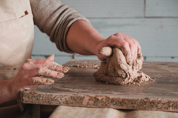 Primo piano mani femminili mescolando palla di argilla prima di lavorare su una ruota di ceramica
 - Foto, immagini