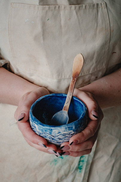Close-up woman in apron holding hand made ceramic pottery designer painted bowl - Fotoğraf, Görsel