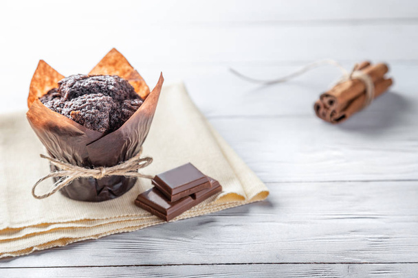 Muffin de chocolate hecho a mano con trozos de chocolate y canela en una mesa de madera con espacio para copiar
 - Foto, Imagen