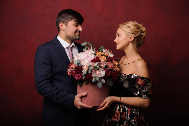 Young man and woman holding the bouquet of flowers looking into eyes - Fotografie, Obrázek