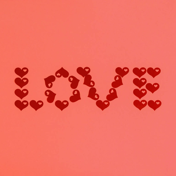 Text LOVE made of red confetti hearts on living coral background. Love, romance or Valentine's day concept. Color of the year 2019 - Photo, Image