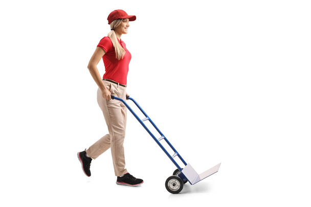 Full length shot of a young female worker pushing an empty hand truck isolated on white background - Fotoğraf, Görsel