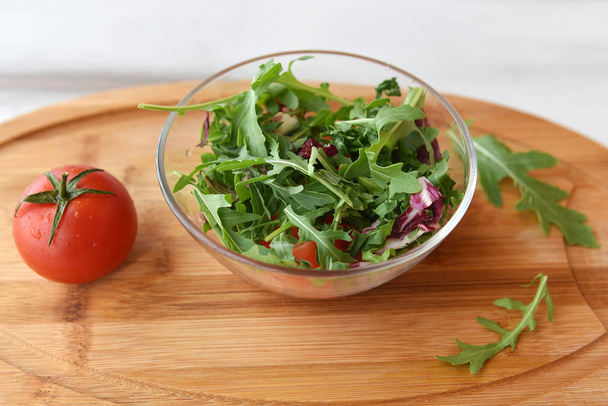 on a wooden background, a plate with fresh herbs, arugula and cabbage. near a tomato. space for text - Fotoğraf, Görsel