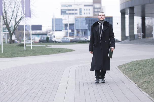 businessman in warm clothes walking down the street of the city. - Zdjęcie, obraz