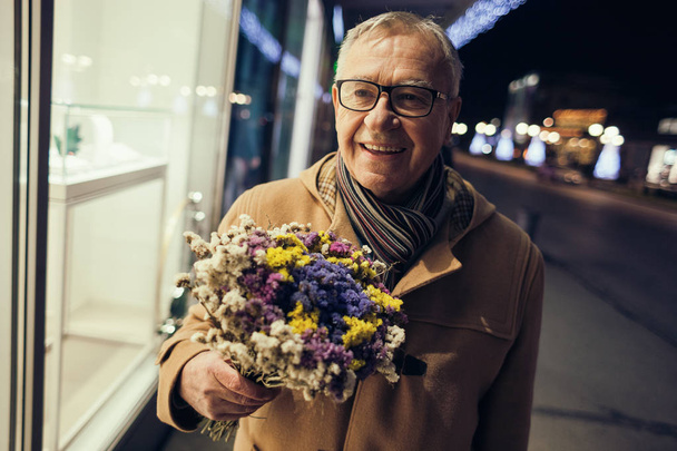 Ευτυχής ανώτερος άνθρωπος φέρνει λουλούδια στη γυναίκα του.  - Φωτογραφία, εικόνα