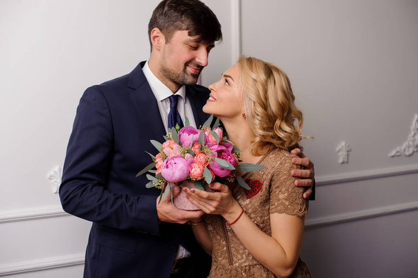 Young man hugging his woman with the bouquet of flowers and looking into eyes - Photo, image