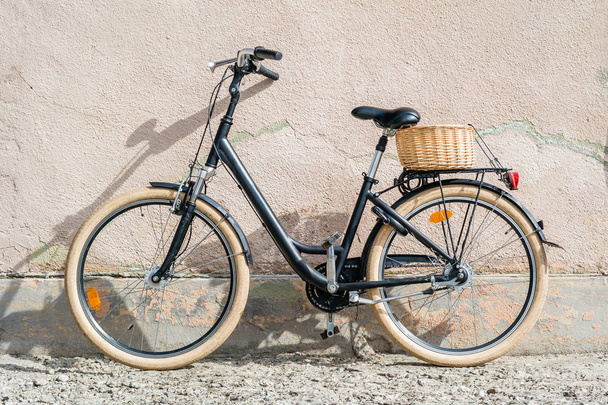 Черный ретро-винтажный велосипед. Ретро велосипед с корзиной перед старой стеной
.  - Фото, изображение