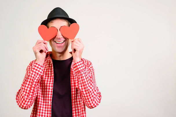 Romantic guy holds valentine cards. Be my valentine. Boyfriend showing love fun affection. Happy man in love. Happy Valentines Day. Funny man covers eyes with red hearts - Foto, imagen
