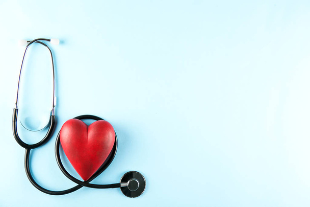 Heart disease awareness and prevention concept. Stethoscope and red heart on pale blue isolated background with a lot of copy space for text. Close up, top view. Medical equipment for cardiologist. - Fotografie, Obrázek