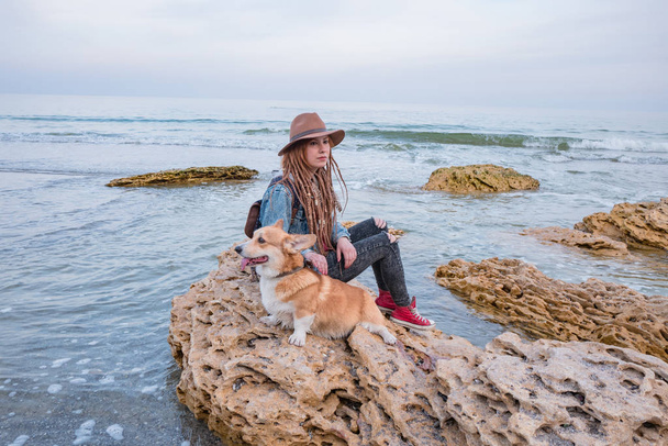 young woman with corgi dog relaxing on autumn beach - 写真・画像