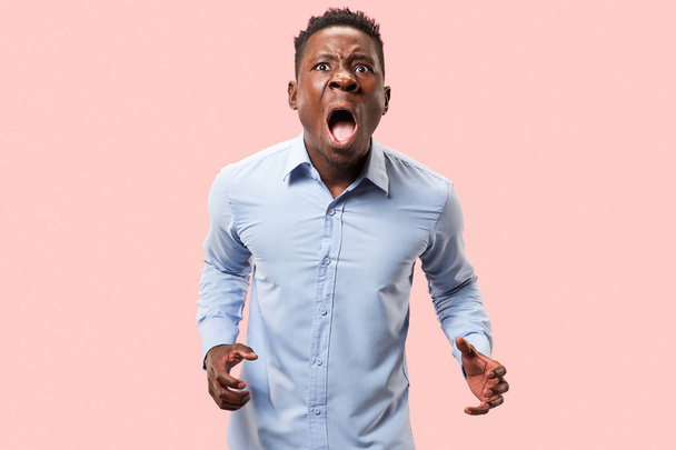 The young emotional angry man screaming on pink studio background - Фото, зображення