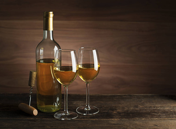Bottle of white wine with wine glasses on wooden background - Fotoğraf, Görsel