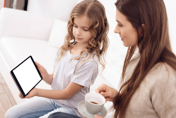 Cute curly girl with beautiful brown hair mother choose hairstyle on tablet. - Valokuva, kuva