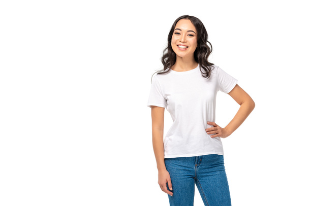 attraente asiatico femmina in bianco t-shirt e blu jeans tenendo mano su anca isolato su bianco
 - Foto, immagini