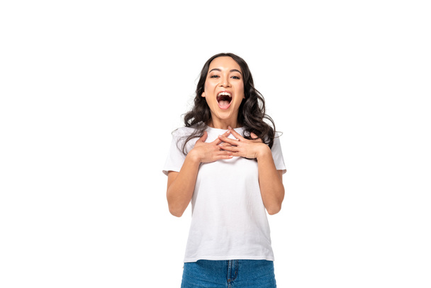 Emocionado mujer asiática en camiseta blanca cogida de la mano en el pecho aislado en blanco
 - Foto, imagen