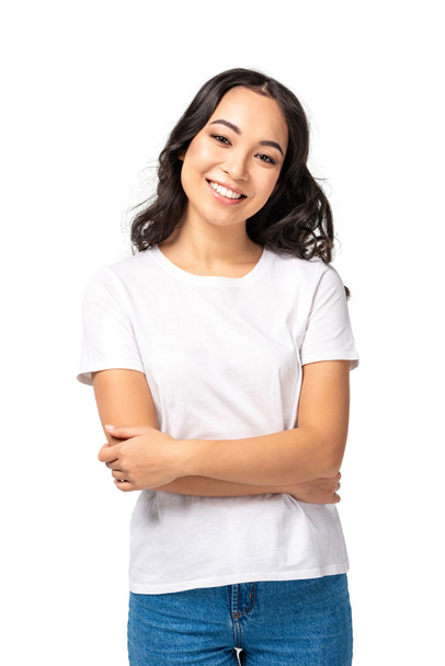 Uśmiechnięta Azjatka młodej kobiety w biały t-shirt stojący ze skrzyżowanymi rękami na białym tle - Zdjęcie, obraz