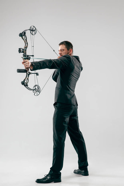 Businessman aiming at target with bow and arrow, isolated on white background - 写真・画像