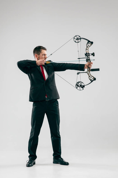 Businessman aiming at target with bow and arrow, isolated on white background - Fotografie, Obrázek