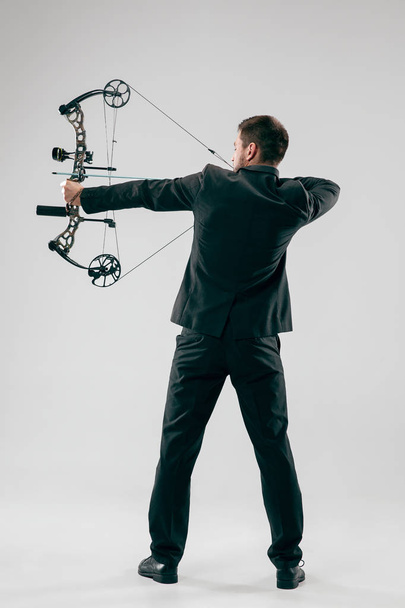 Businessman aiming at target with bow and arrow, isolated on white background - Foto, imagen