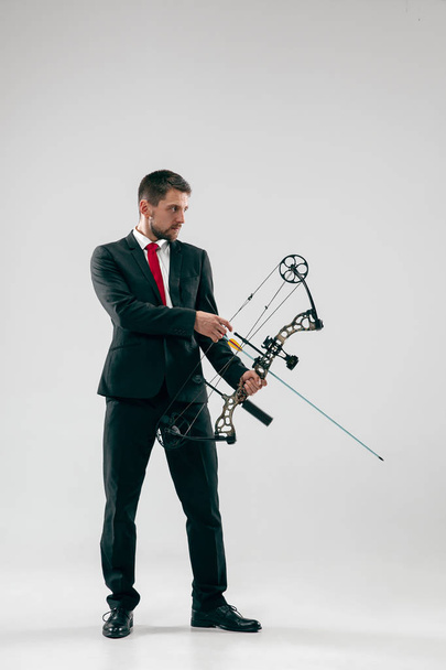 Businessman aiming at target with bow and arrow, isolated on white background - Foto, afbeelding