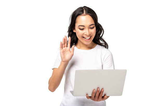 Uśmiechający się młoda kobieta azjatyckich za pomocą laptopa i pokazuje gest Witam na białym tle - Zdjęcie, obraz
