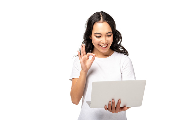 jeune femme asiatique à l'aide d'un ordinateur portable et montrant ok geste isolé sur blanc
 - Photo, image