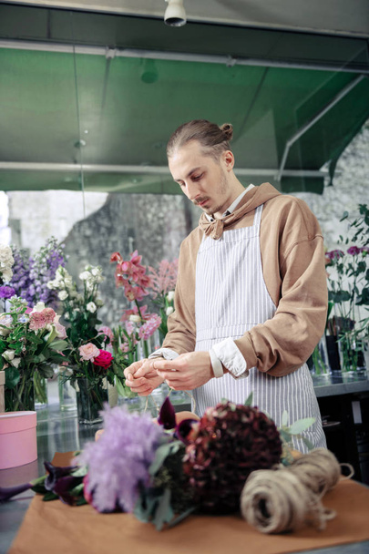 Attentive young designer making bouquet from plants - Photo, image