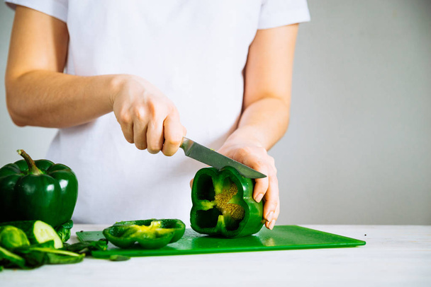 woman cut green paper on green kitchen board - Photo, Image