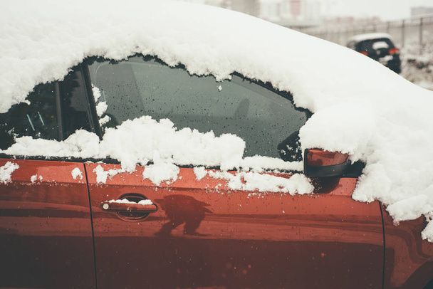 Cide vista del coche rojo en primer plano, cubierto de nieve fresca y esponjosa
 - Foto, imagen