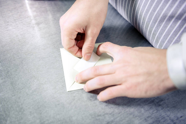 Закрыть руки мужчин, которые прячут бумагу в конверт
 - Фото, изображение