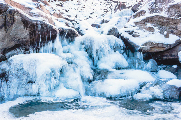 Winter mountain river under ice. Water froze and turned into icicles. - 写真・画像