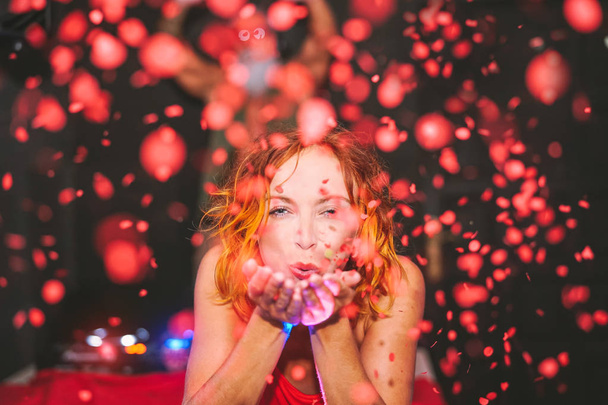 Счастливая женщина бросает конфеты в диско-клуб - Молодая девушка весело празднует в баре - Люди, ночная жизнь, ночной клуб и концепция молодежных праздников
 - Фото, изображение