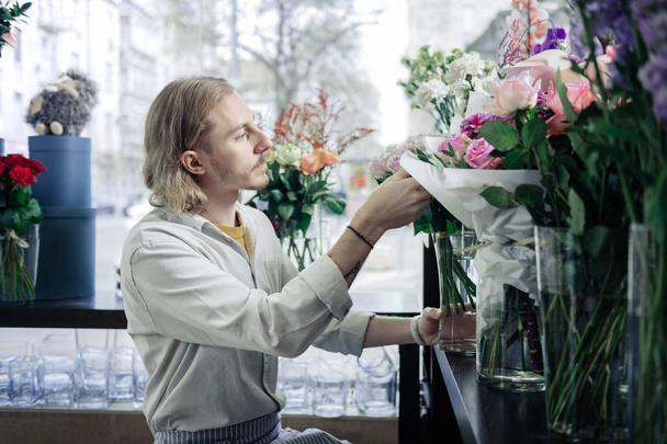 Attentive young man taking flowers from vase - Valokuva, kuva