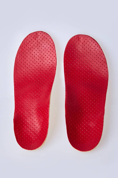Ortesis sobre fondo blanco. Insertar en los zapatos para apoyar el pie. Plantilla médica de cuero rojo
  - Foto, Imagen