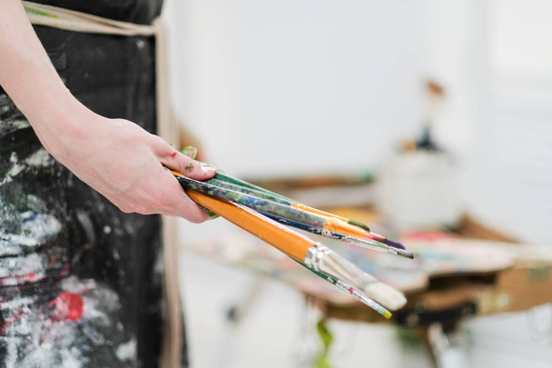 Artists tools on the easel. Brushes, paints and canvas. - 写真・画像