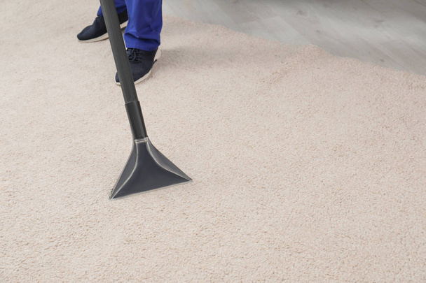Man removing dirt from carpet with vacuum cleaner indoors, closeup. Space for text - Fotó, kép