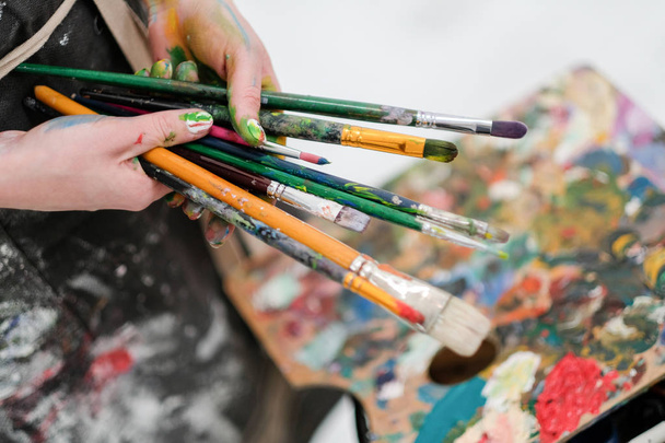 Artists tools on the easel. Brushes, paints and canvas. - 写真・画像