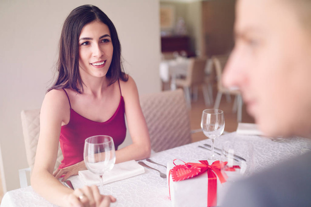 Valentine's Day concept. Happy couple in love with. A young loving couple celebrating Valentine's Day in the restaurant. Lovers give each other gifts. Romance restaurant for Valentine's Day- concept. - Photo, image